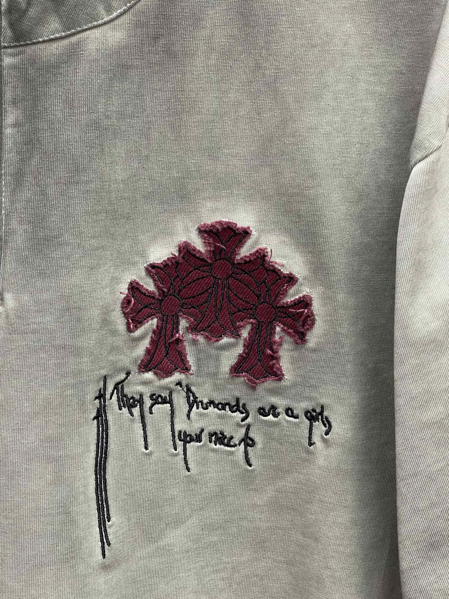 Burgundy cross and script embroidery on a light gray T-shirt