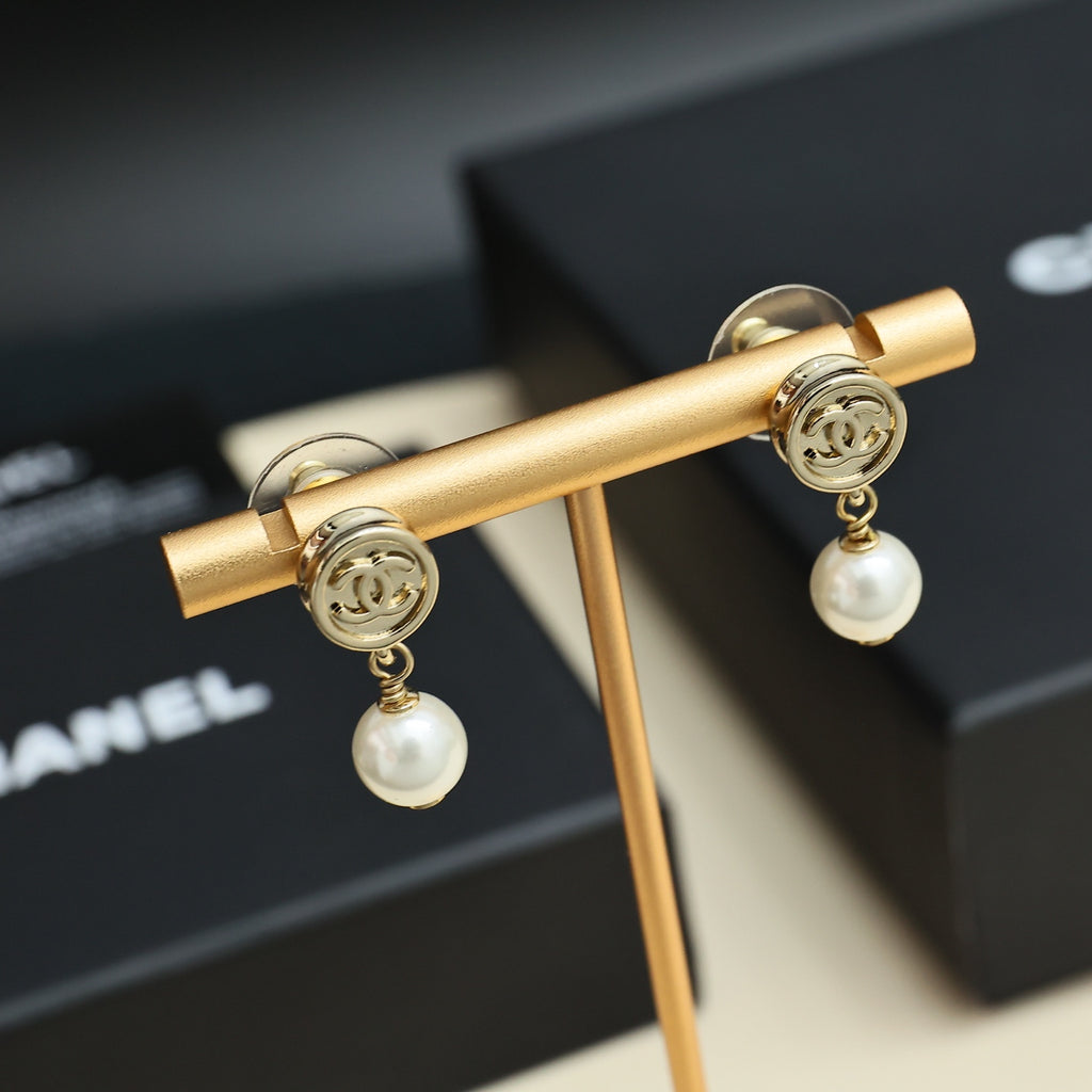 Chanel CC gold-tone pearl drop earrings on gold display bar