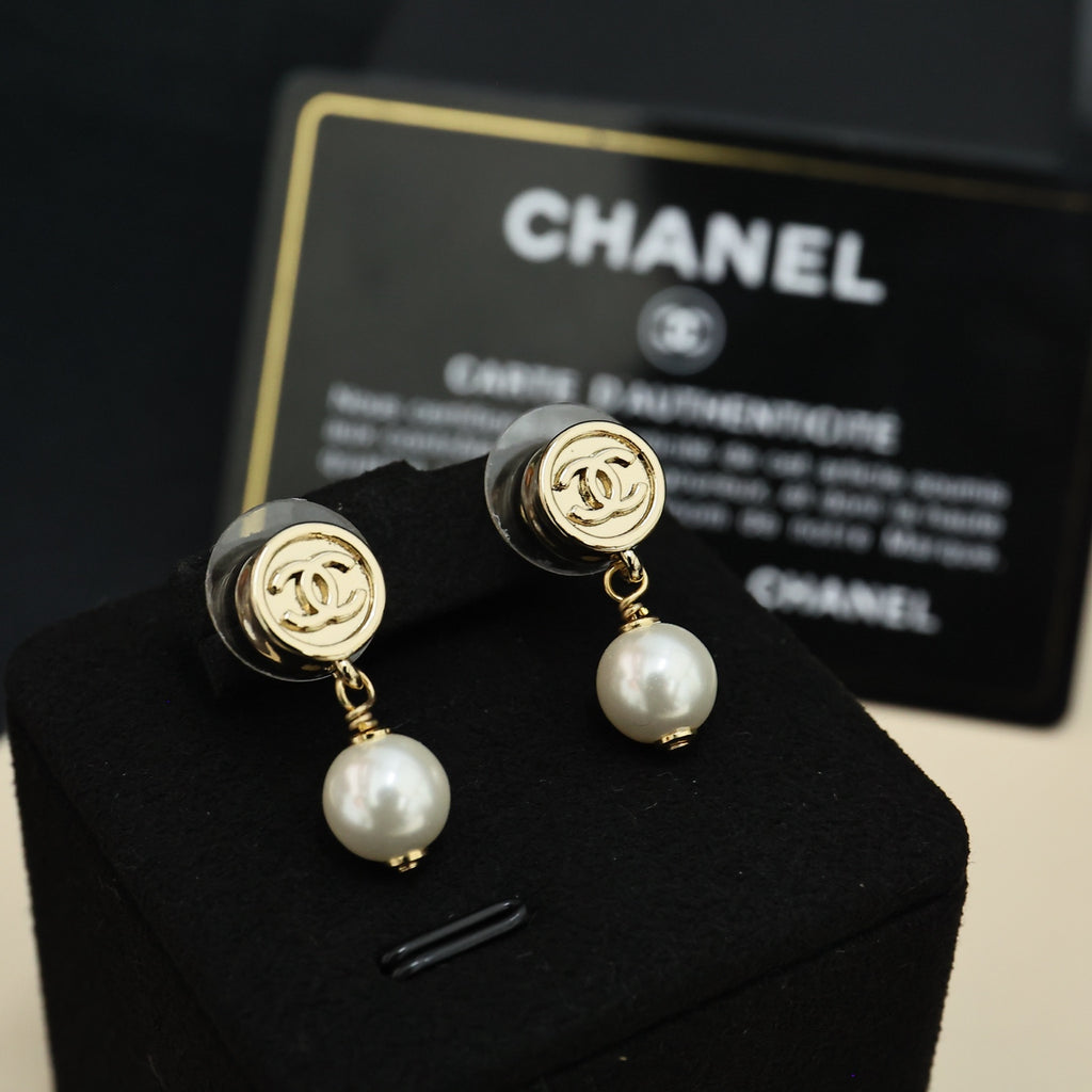 Chanel CC gold-tone pearl drop earrings on black display