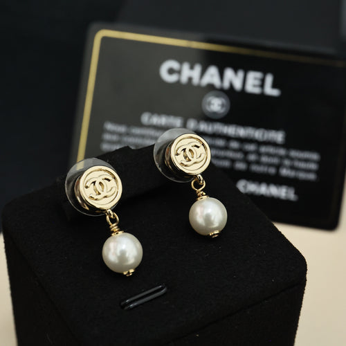 Chanel CC gold-tone pearl drop earrings on black display