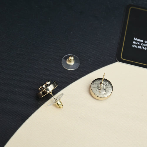 Chanel stud earrings showing gold-tone posts and round blue enamel face