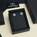 Chanel stud earrings in a black jewelry box with two blue-and-gold logos