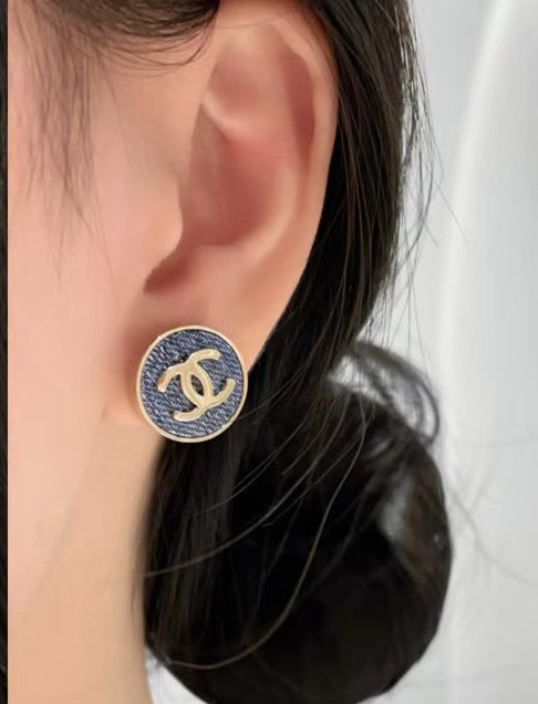 Chanel logo stud earrings worn on ear, blue enamel round face in gold-tone
