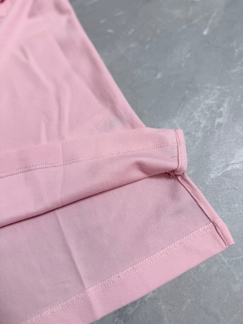 Pink polo shirt cuff with stitched edge and side seam
