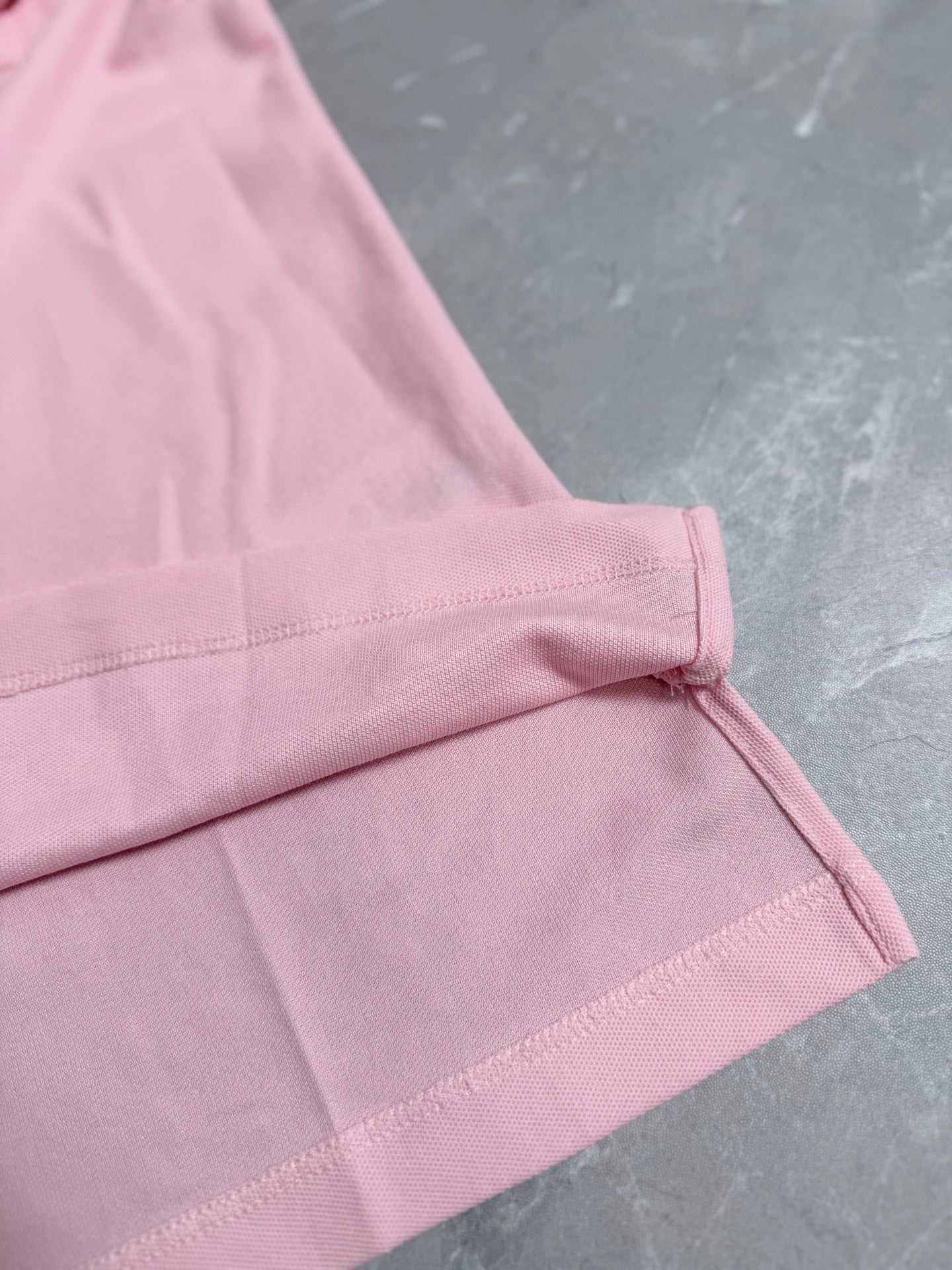 Pink polo shirt cuff with stitched edge and side seam