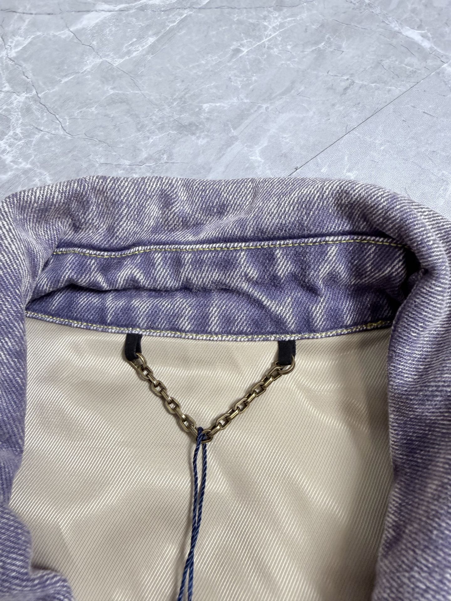 Louis Vuitton denim jacket neckline with chain and logo hang tag detail