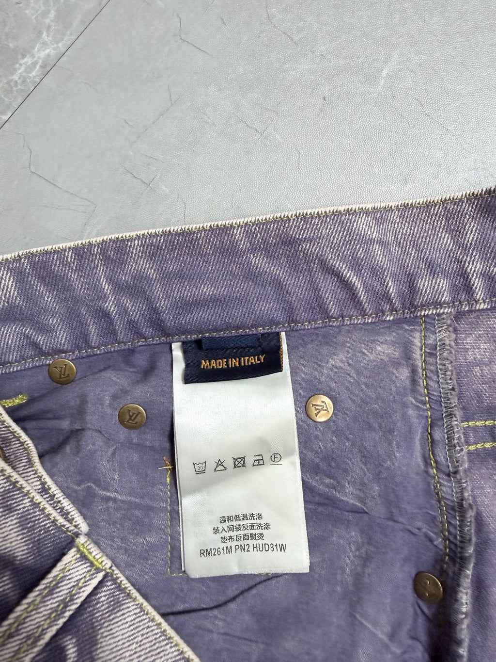 Denim pants waistband detail with gold logo buttons and white brand tag