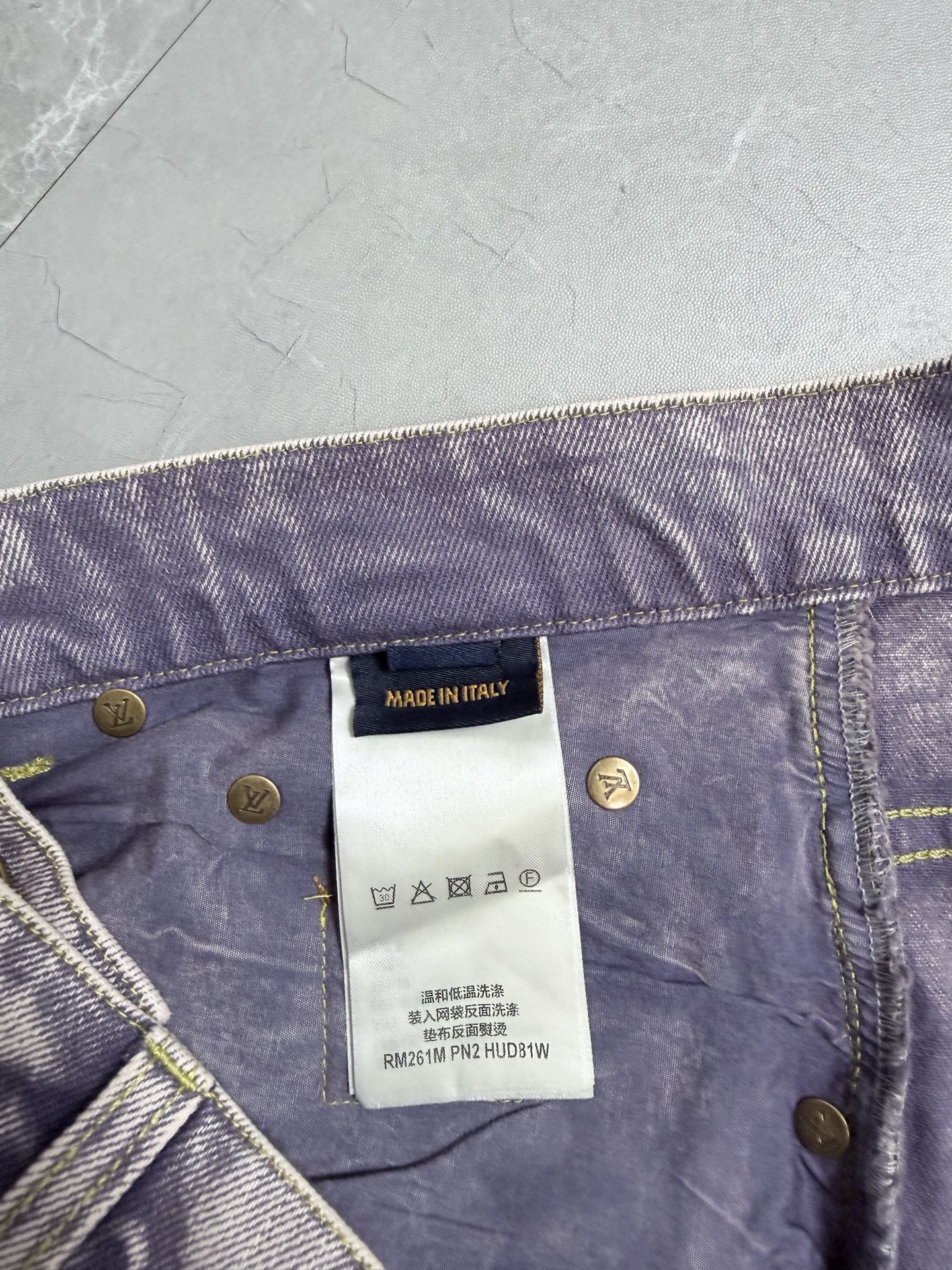 Denim pants waistband detail with gold logo buttons and white brand tag