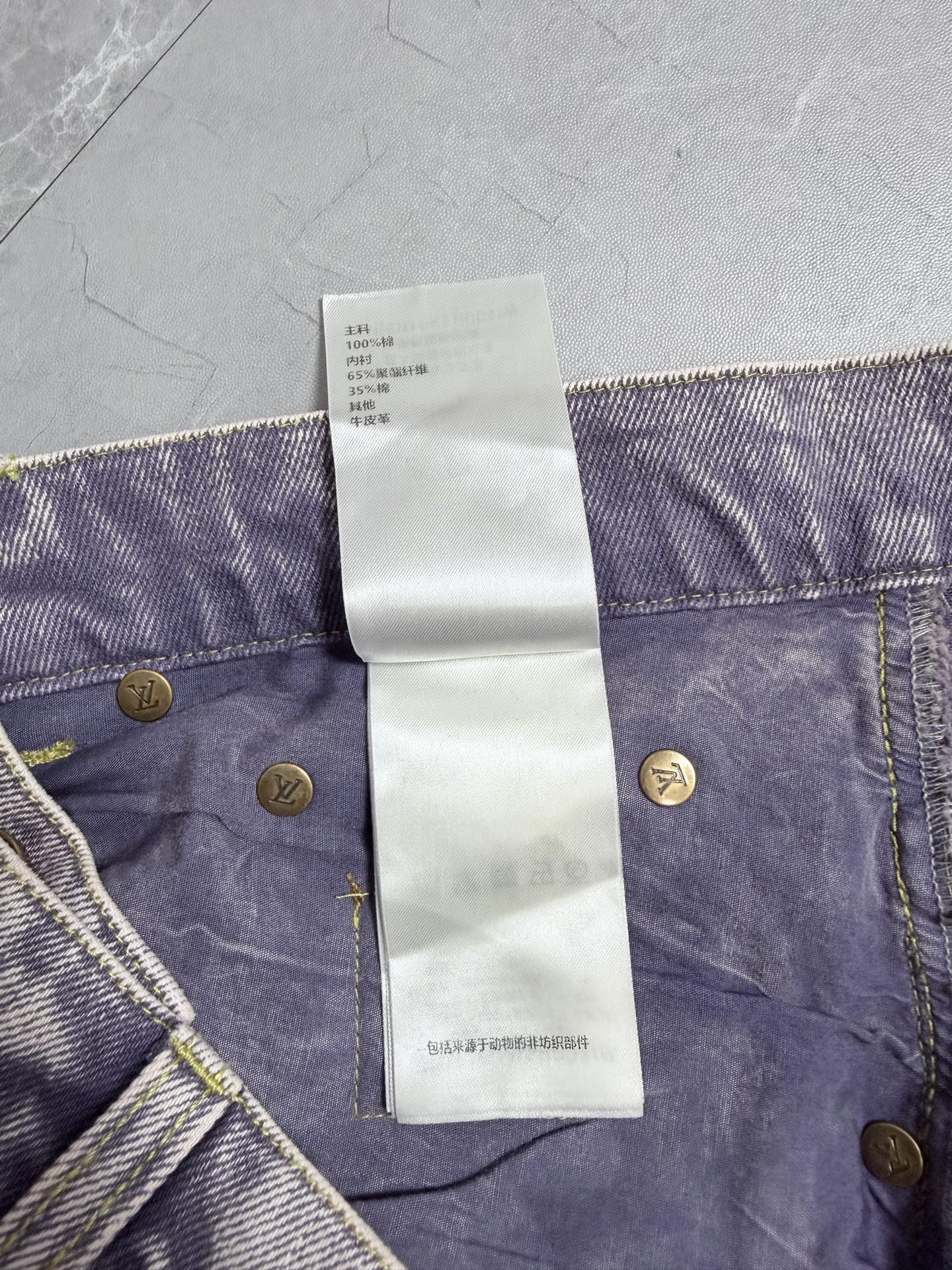 Denim pants waistband with white care label tag and gold button details