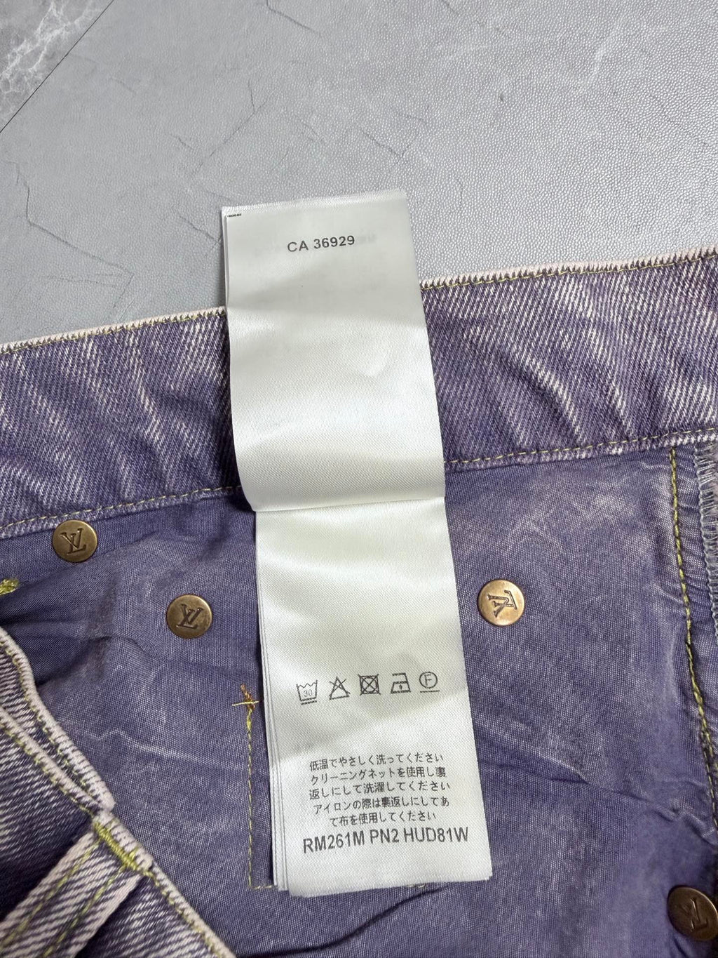 Denim pants waistband with care symbol icons on white tag and gold button