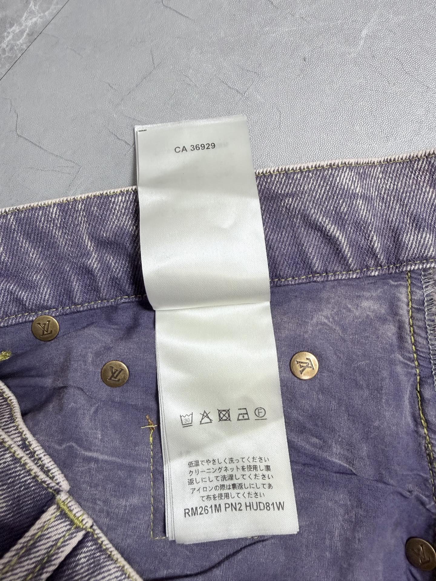 Denim pants waistband with care symbol icons on white tag and gold button