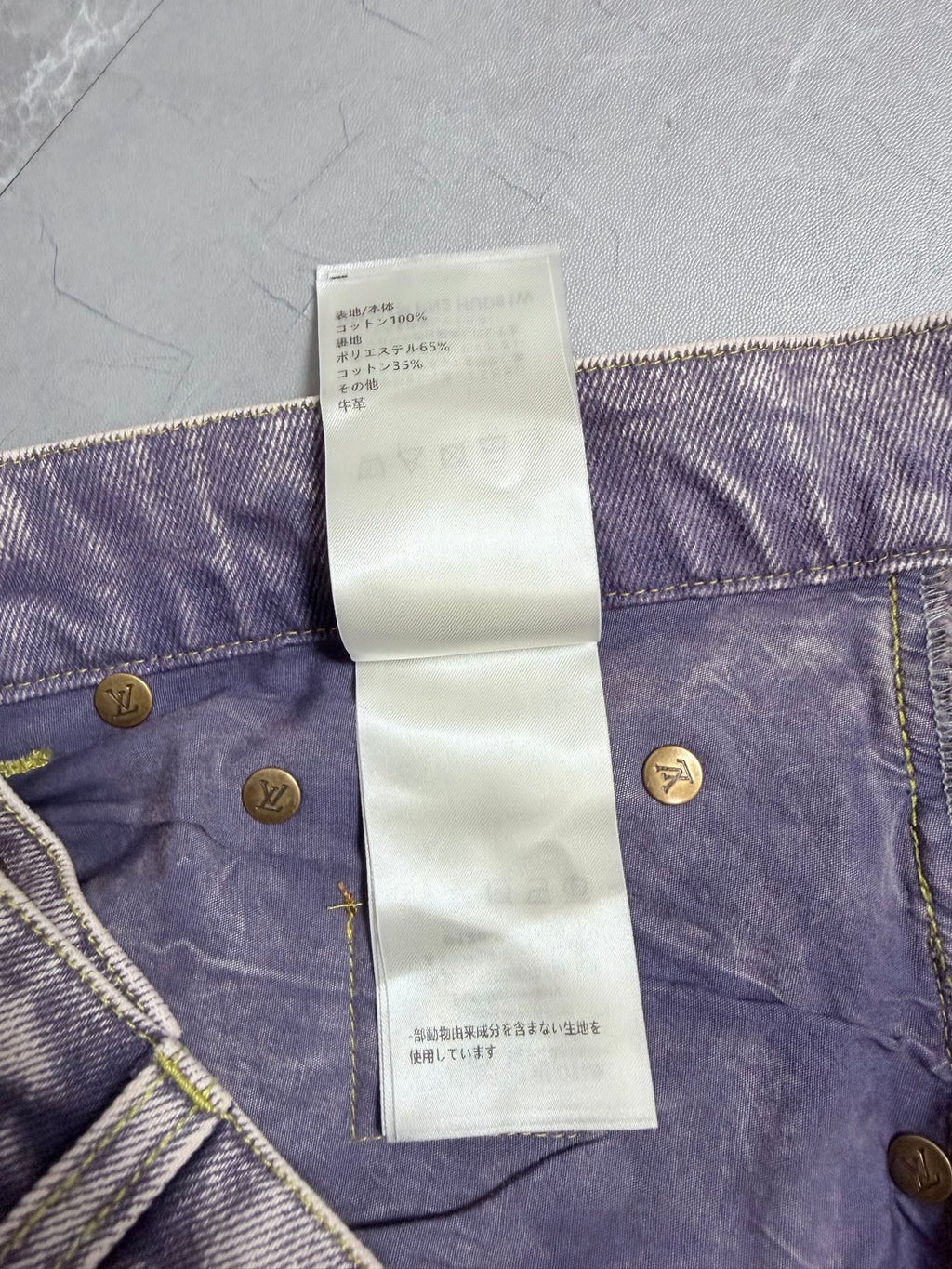 Denim pants waistband with white care label text and gold button