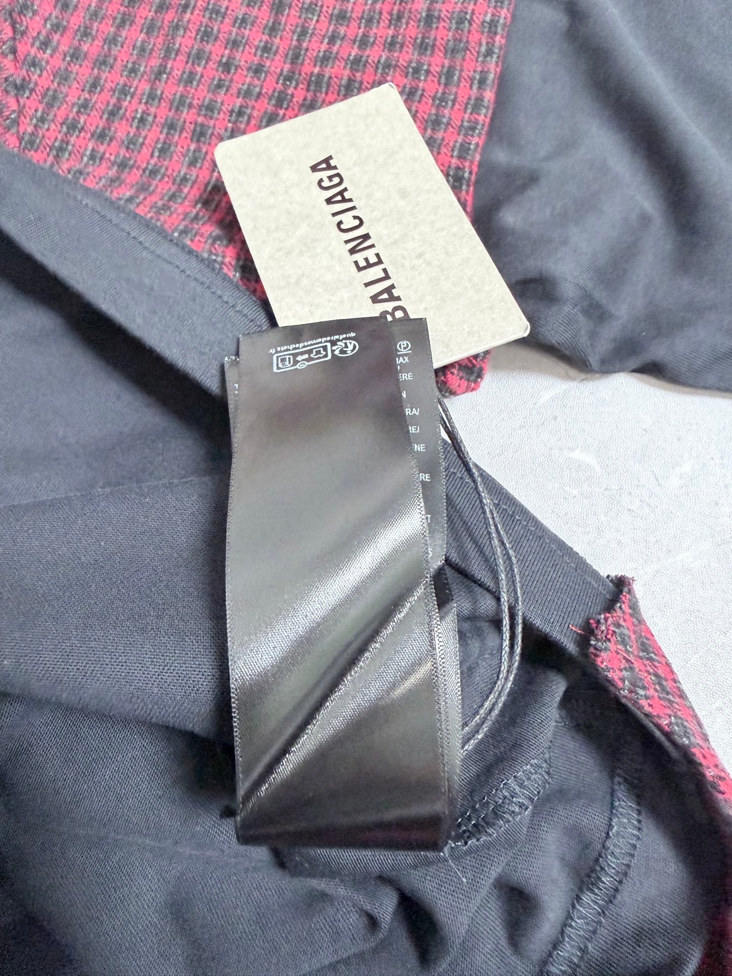 Long-sleeve jacket fabric close-up with dark gray body, burgundy check accents, fabric label
