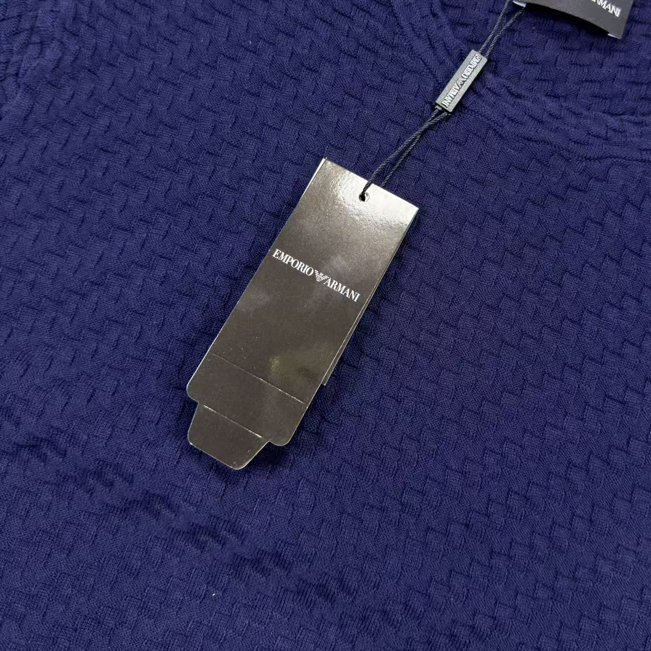 Dark blue textured knit sweater with neck tag and fabric weave detail