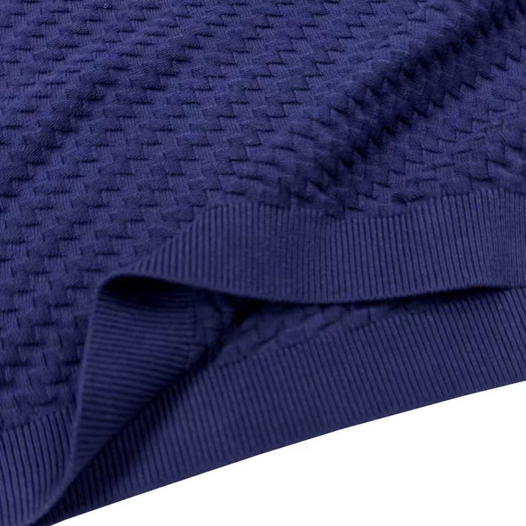 Dark blue knit sweater fabric close-up with ribbed edge at hem