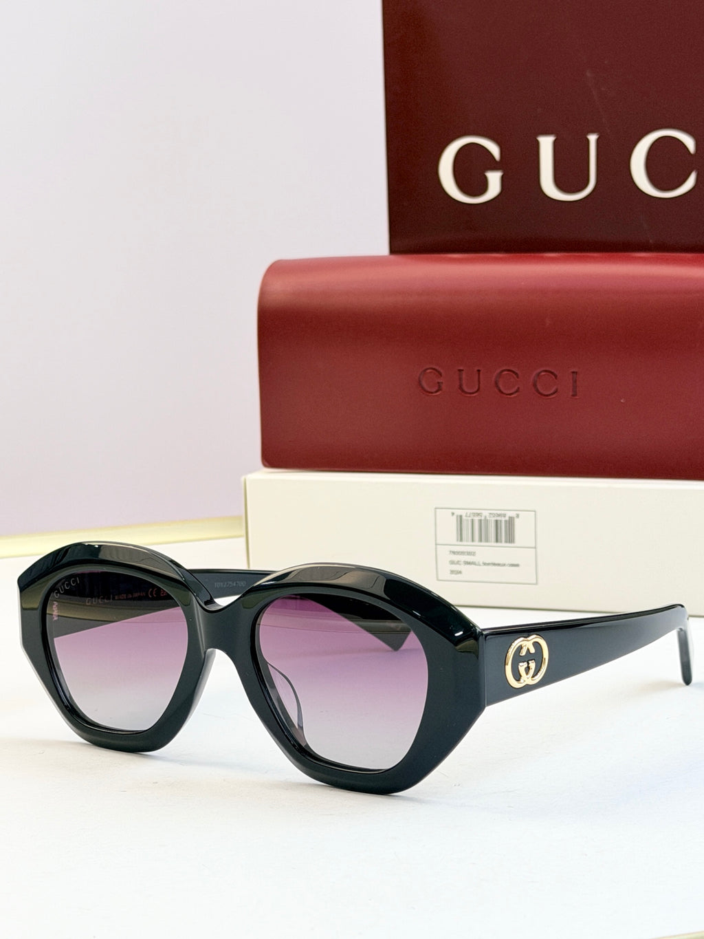 Black round sunglasses with purple-tinted lenses and gold double-G logo on temples
