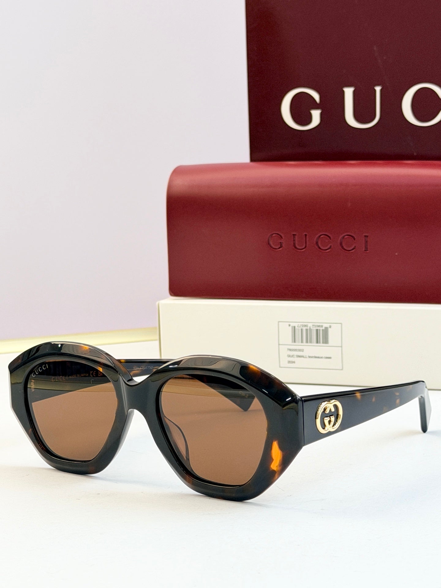 Black round sunglasses with amber-tinted lenses and gold double-G logo on temples