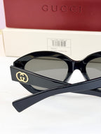 Black sunglasses with gold double-G logo on temple and gray-tinted lenses