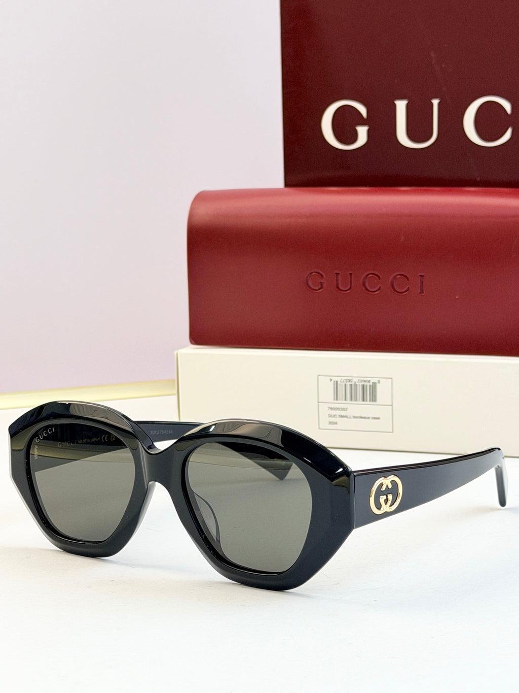 Black round sunglasses with green-tinted lenses and gold double-G logo on temples