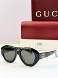 Black round sunglasses with green-tinted lenses and gold double-G logo on temples