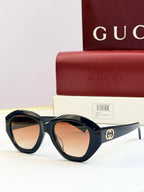 Black round sunglasses with orange-tinted lenses and gold double-G logo on temples