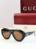 Black round sunglasses with brown-tinted lenses and gold double-G logo on temples