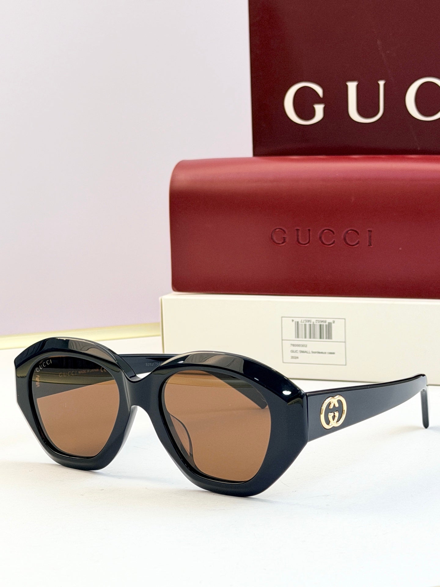Black round sunglasses with brown-tinted lenses and gold double-G logo on temples