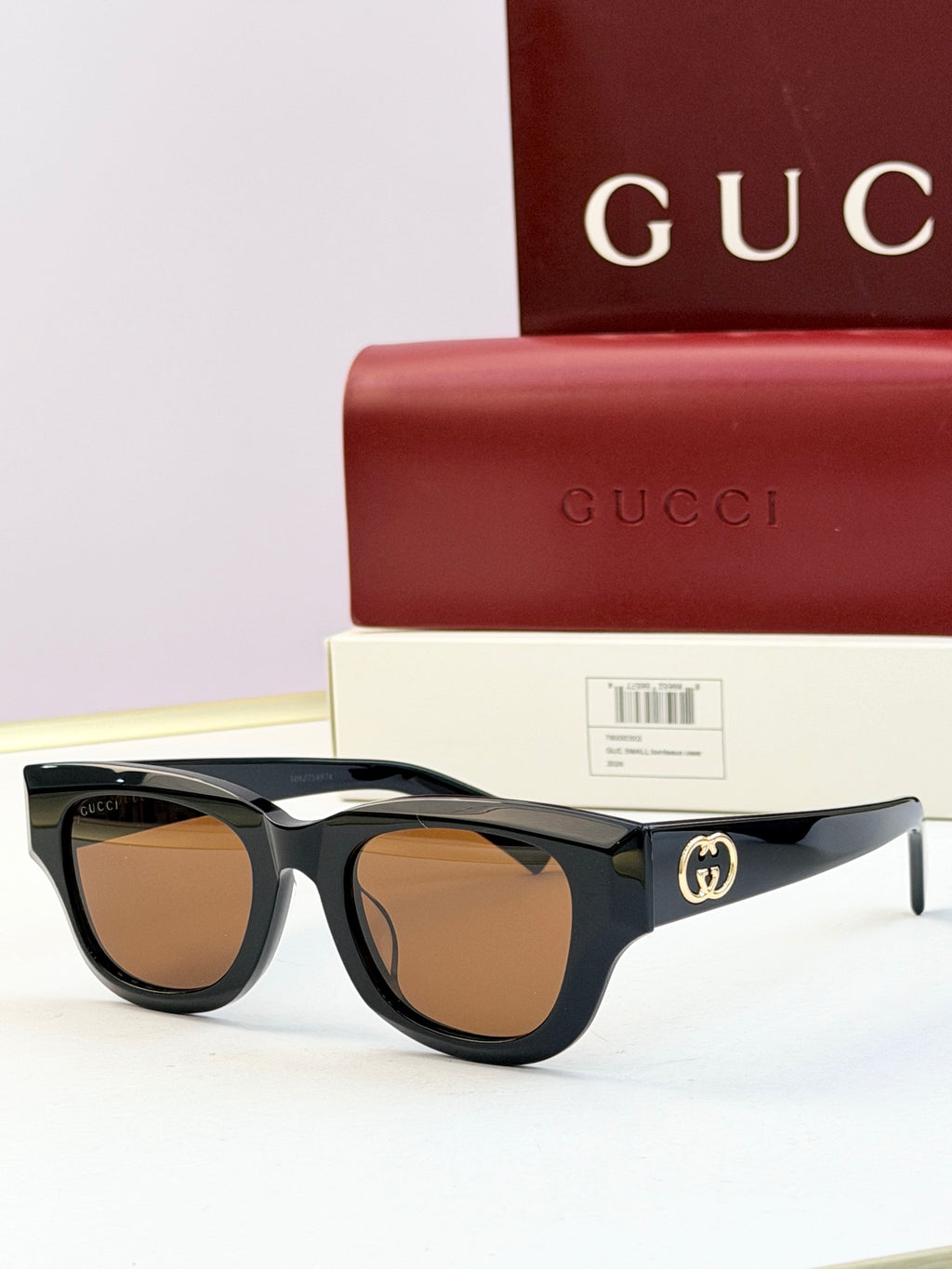 Gucci sunglasses with black acetate frames and warm brown-tinted lenses, gold logo on temple