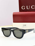Gucci sunglasses with black acetate frames and gray-tinted lenses, gold logo at temple