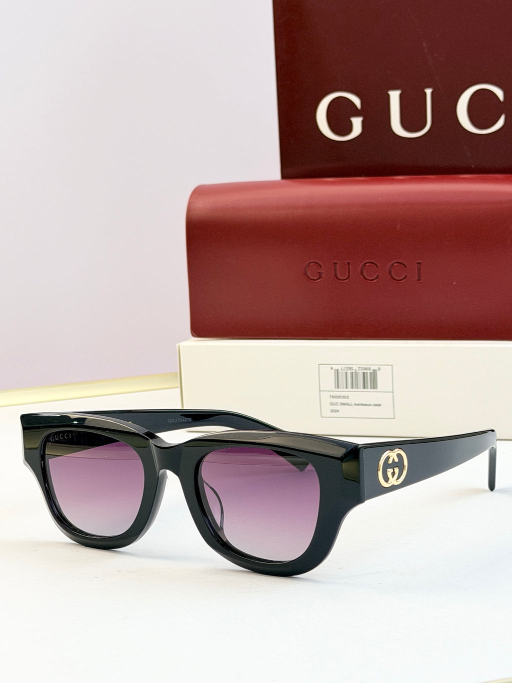Gucci sunglasses with black acetate frames and purple-tinted lenses, gold logo on temple