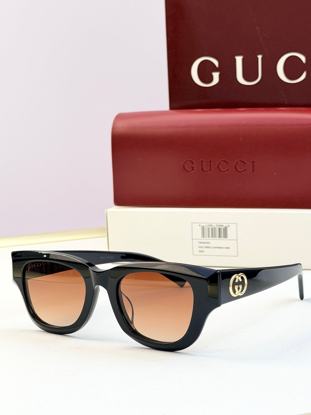 Gucci sunglasses with black acetate frames and brown-tinted lenses, gold logo on temple