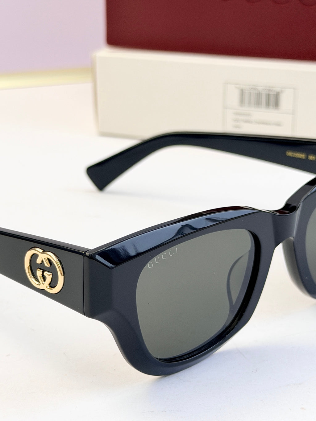 Gucci sunglasses close-up with dark blue frames and gray lenses, gold logo on temple