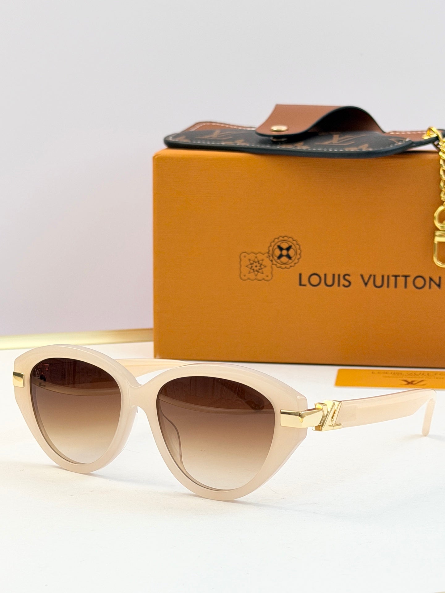 White oval sunglasses with brown-tinted lenses and gold-tone metal arms