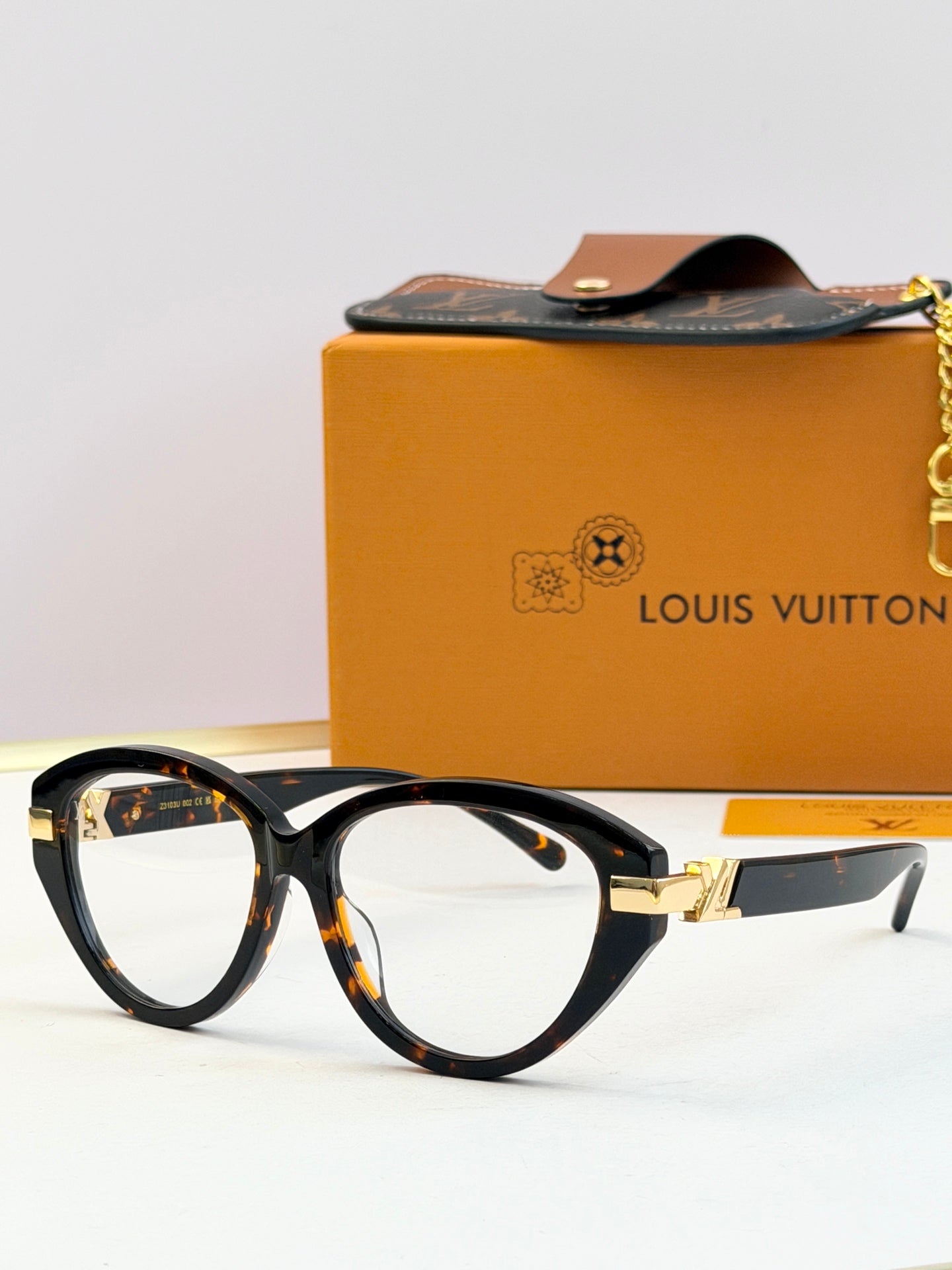 Tortoiseshell oval sunglasses with dark lenses and gold-tone hinge detail