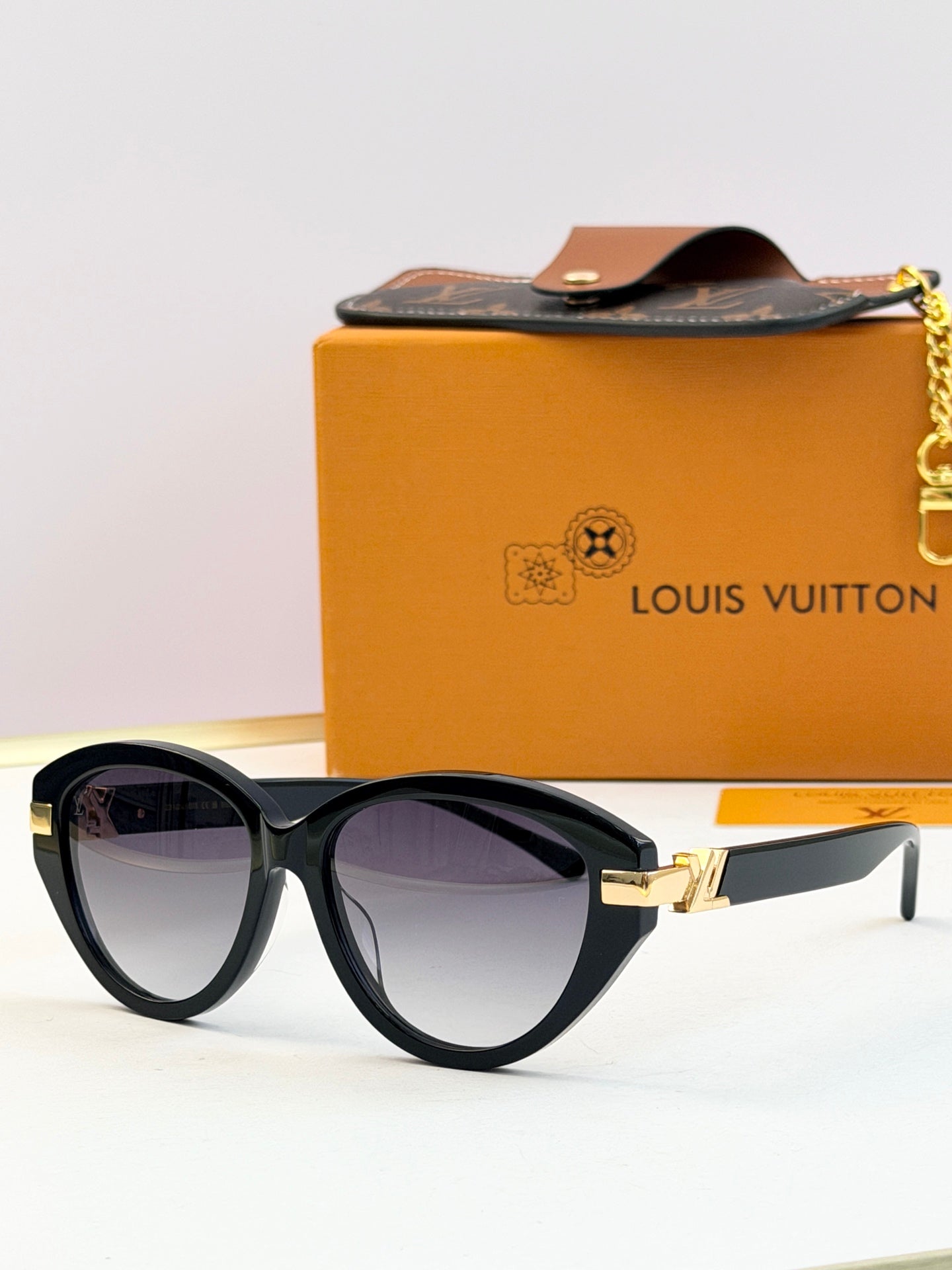 Black oval sunglasses with tinted lenses and gold-tone accent at the hinge