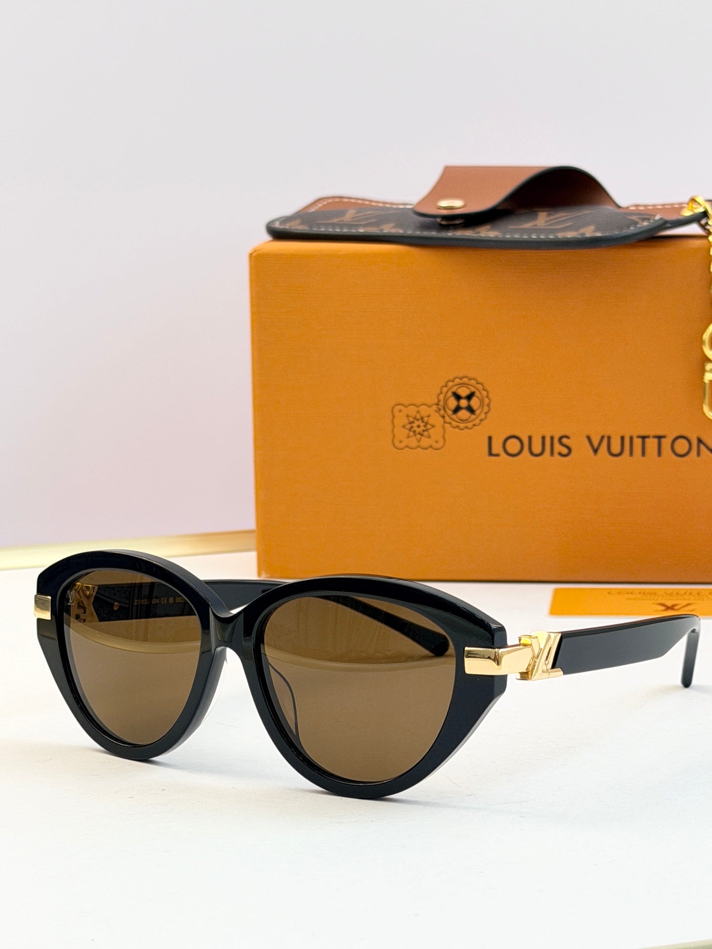 Dark frames oval sunglasses with brown-tinted lenses and gold-tone hinge detail