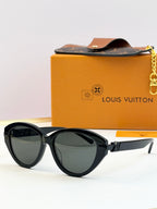 Black oval sunglasses with dark lenses and gold-tone metal arms