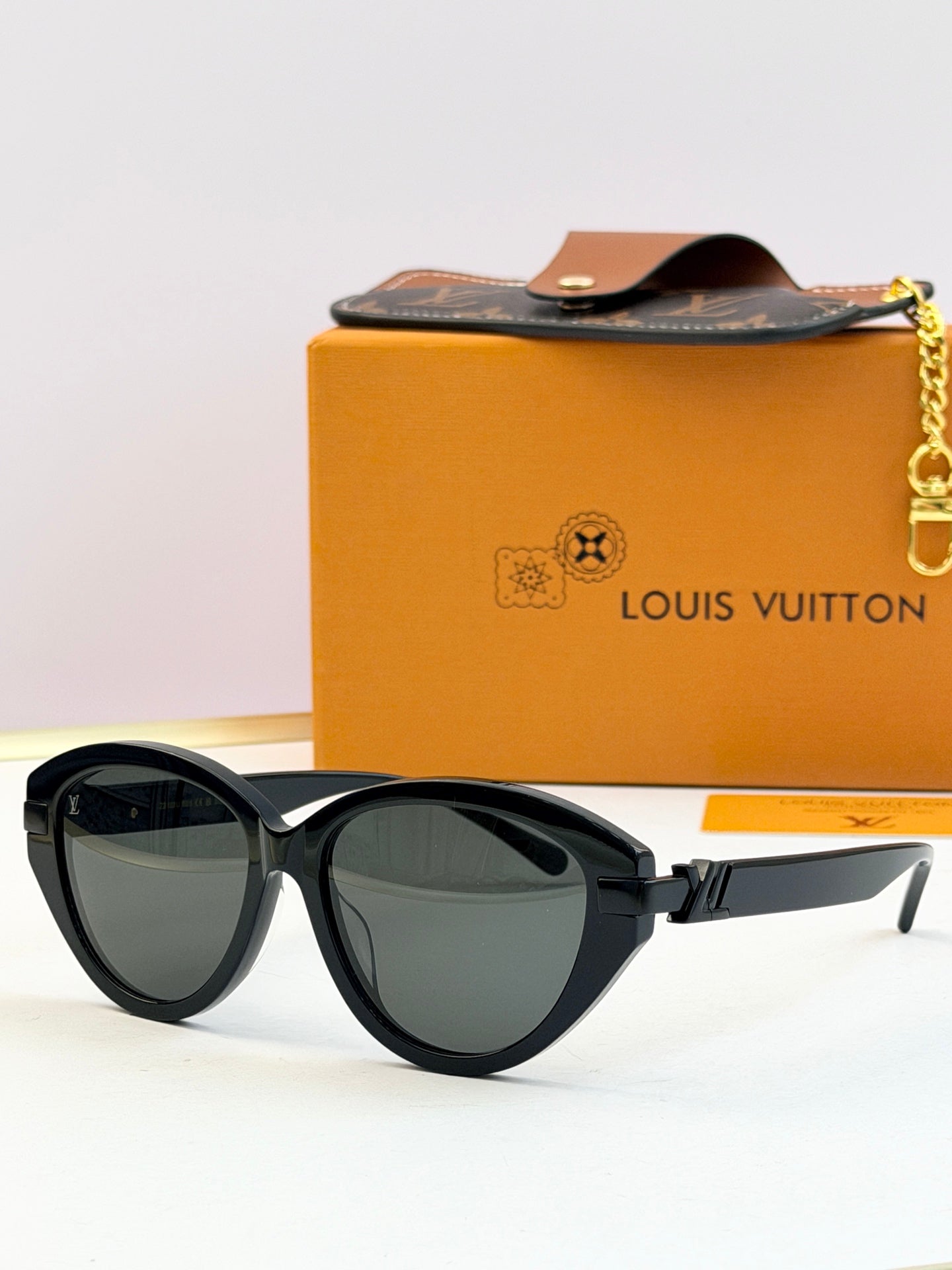 Black oval sunglasses with dark lenses and gold-tone metal arms