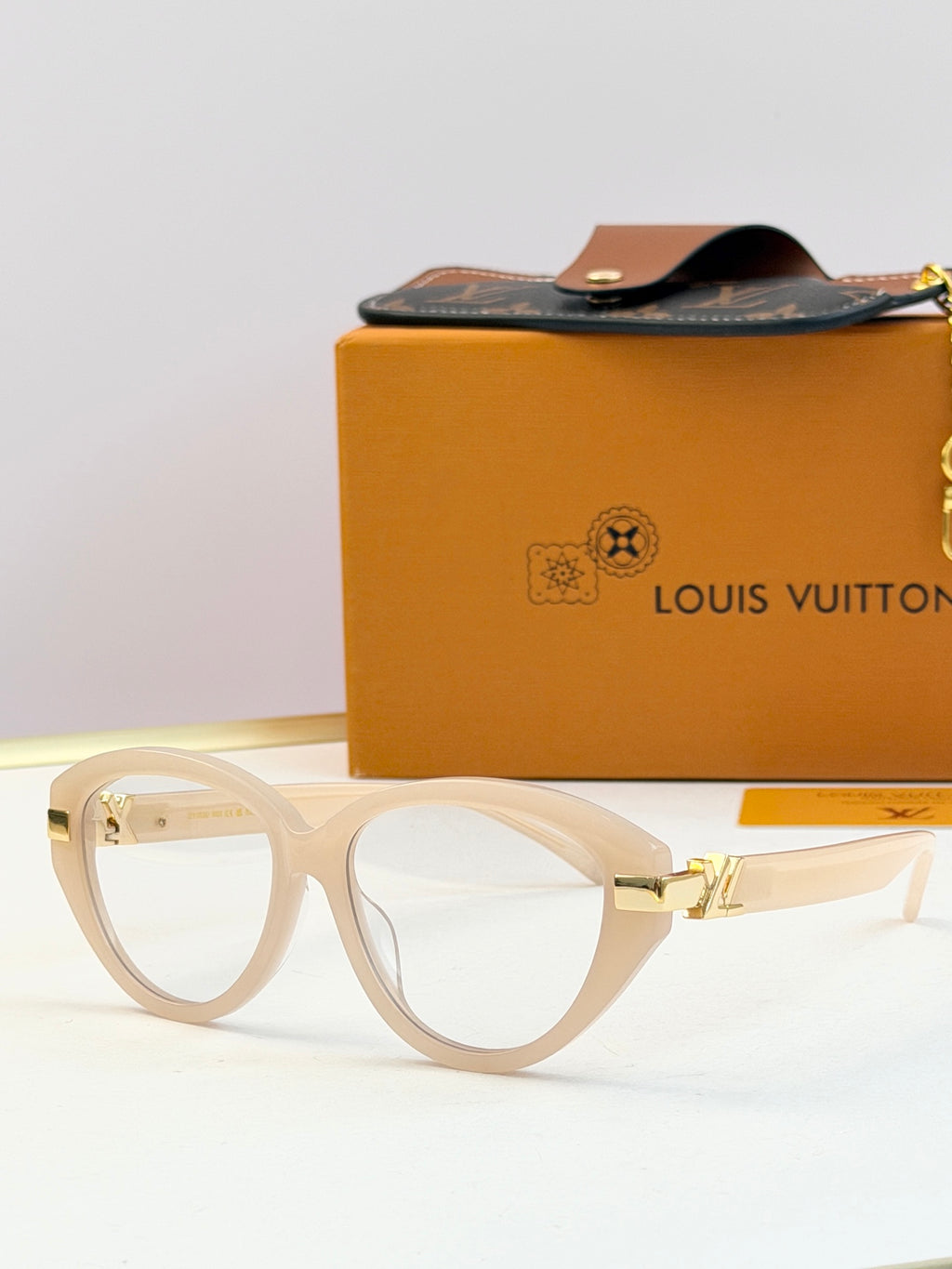 Light-colored oval sunglasses with clear lenses and gold-tone metal arms