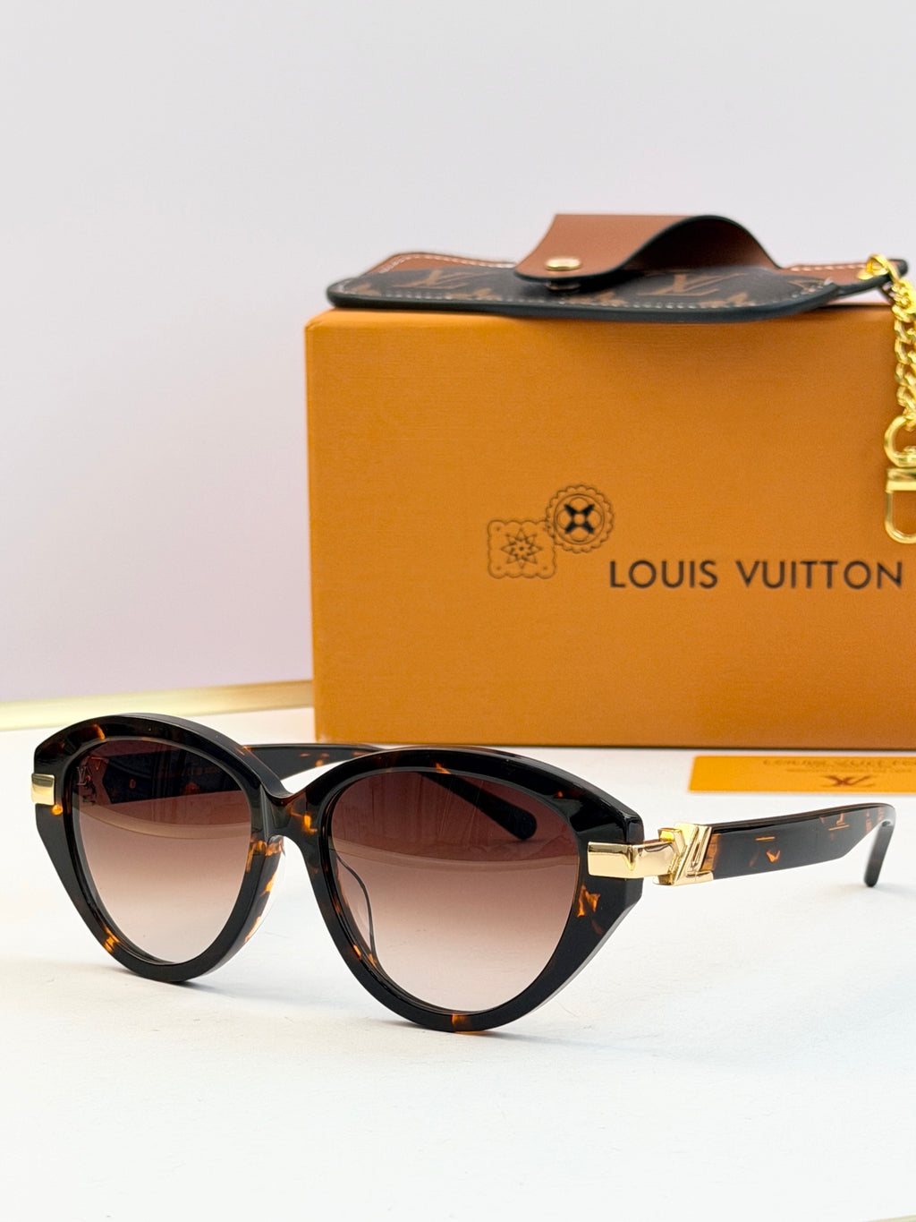 Tortoiseshell oval sunglasses with dark lenses and gold-tone hinge detail