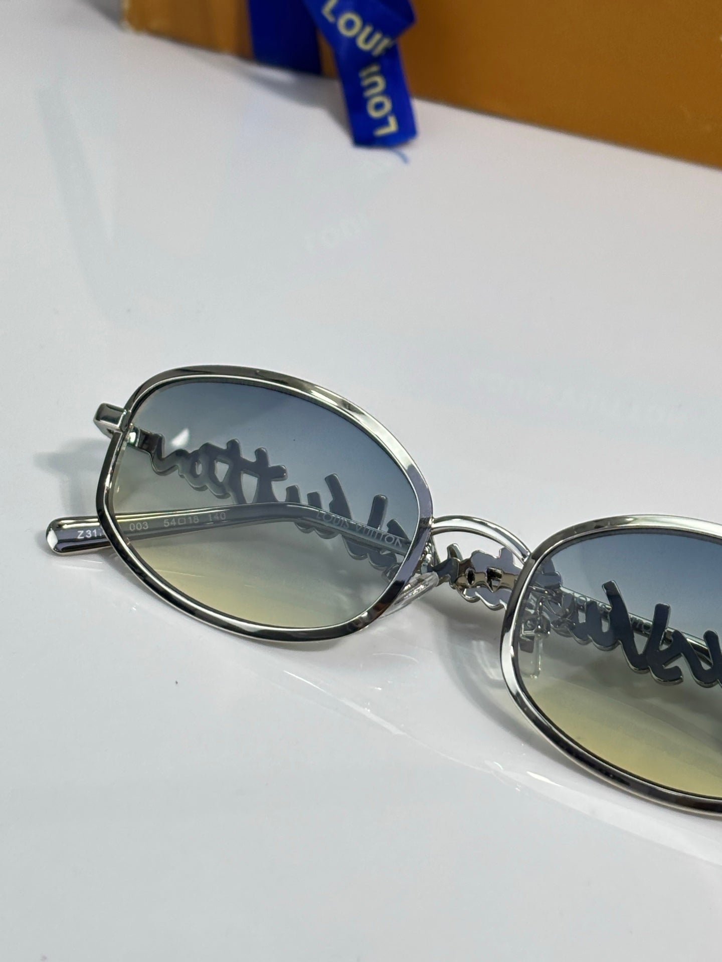 Louis Vuitton sunglasses closeup with oval silver frame and mirrored lenses