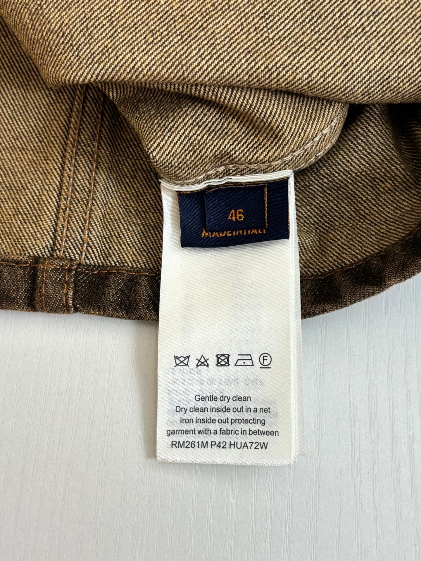 Louis Vuitton long clothing care label on dark brown fabric
