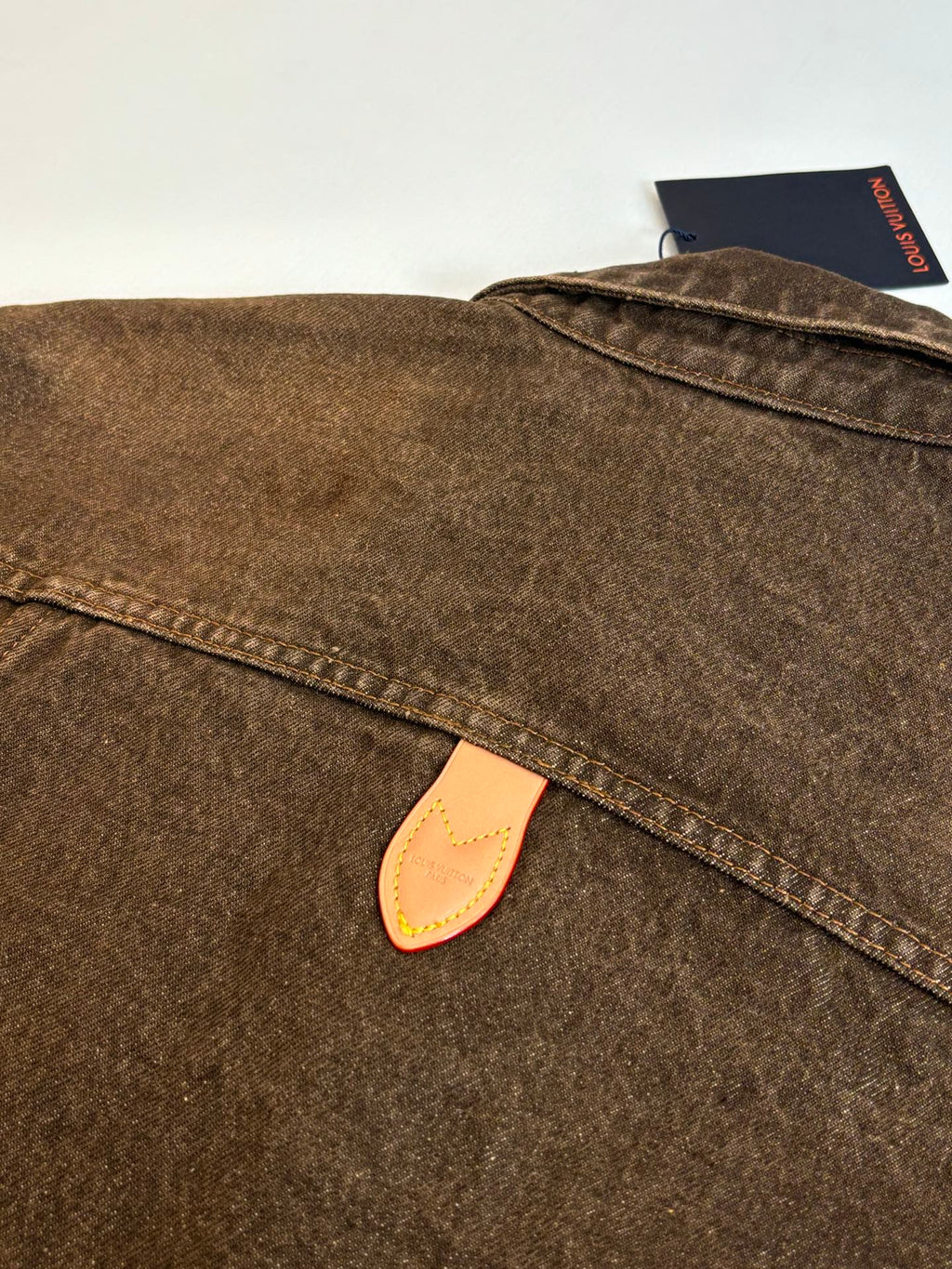 Louis Vuitton brown denim jacket close-up of collar and beige leather logo patch