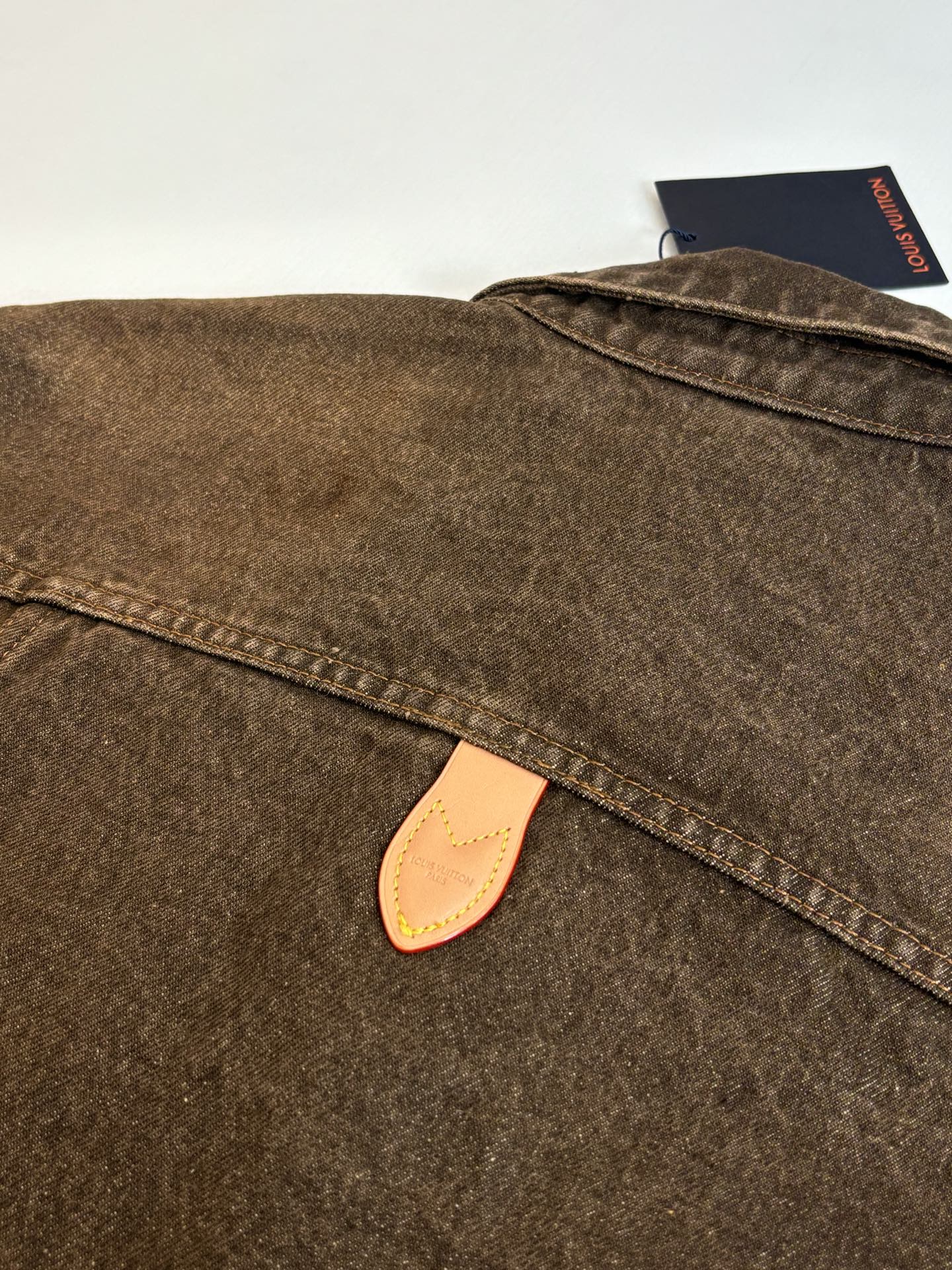 Louis Vuitton brown denim jacket close-up of collar and beige leather logo patch