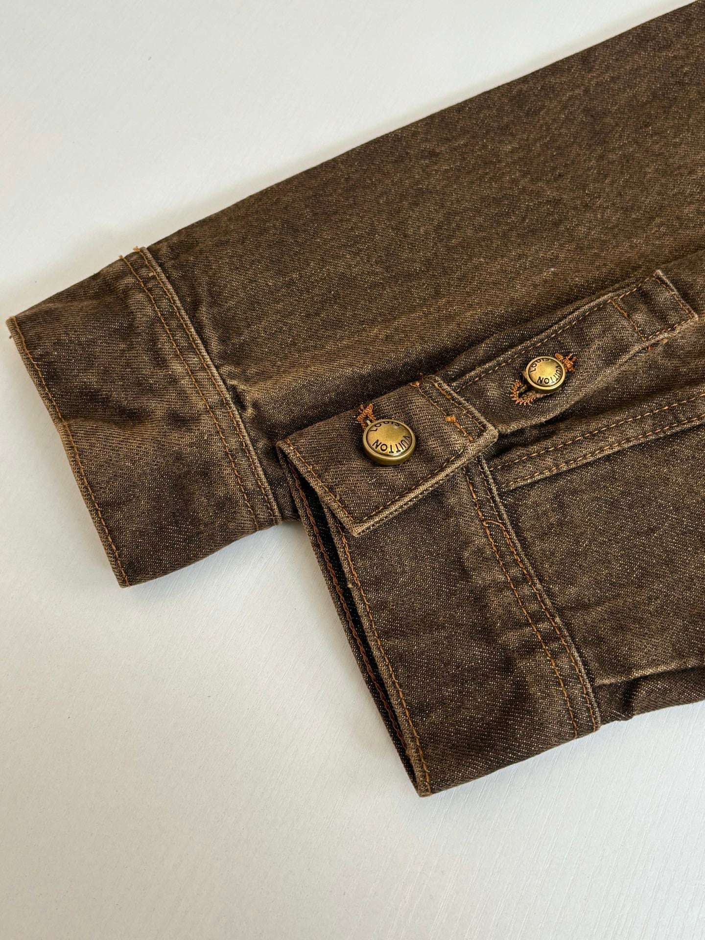 Louis Vuitton brown denim jacket close-up of cuff and two-button pocket flap