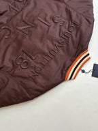 Dark brown long jacket with embroidered LV-style logo and striped orange-white-black trim