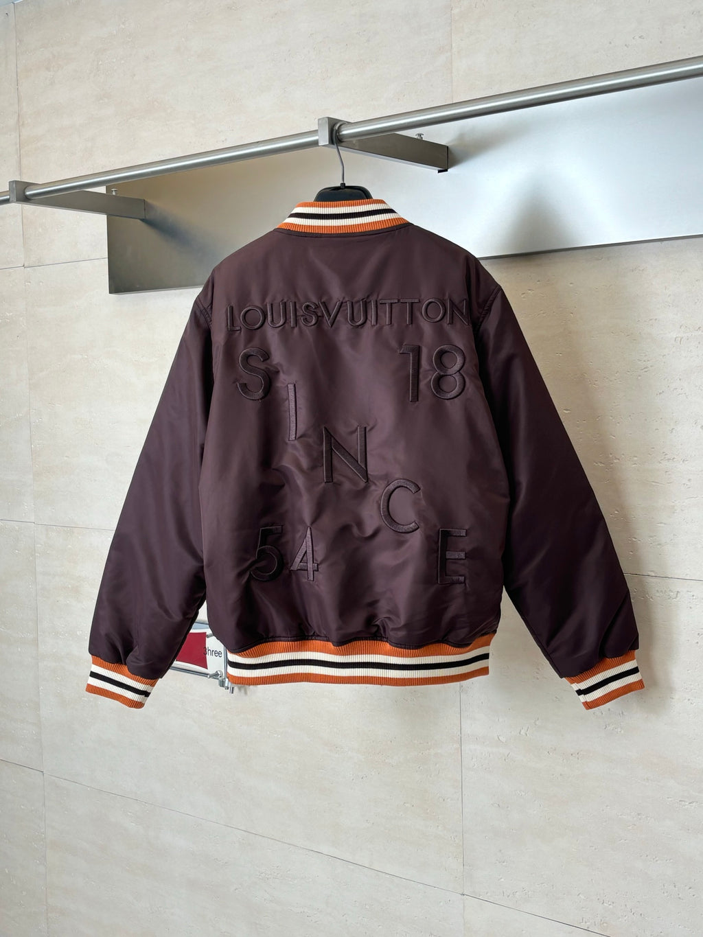 Louis Vuitton long bomber jacket, back view in dark brown with striped rib cuffs