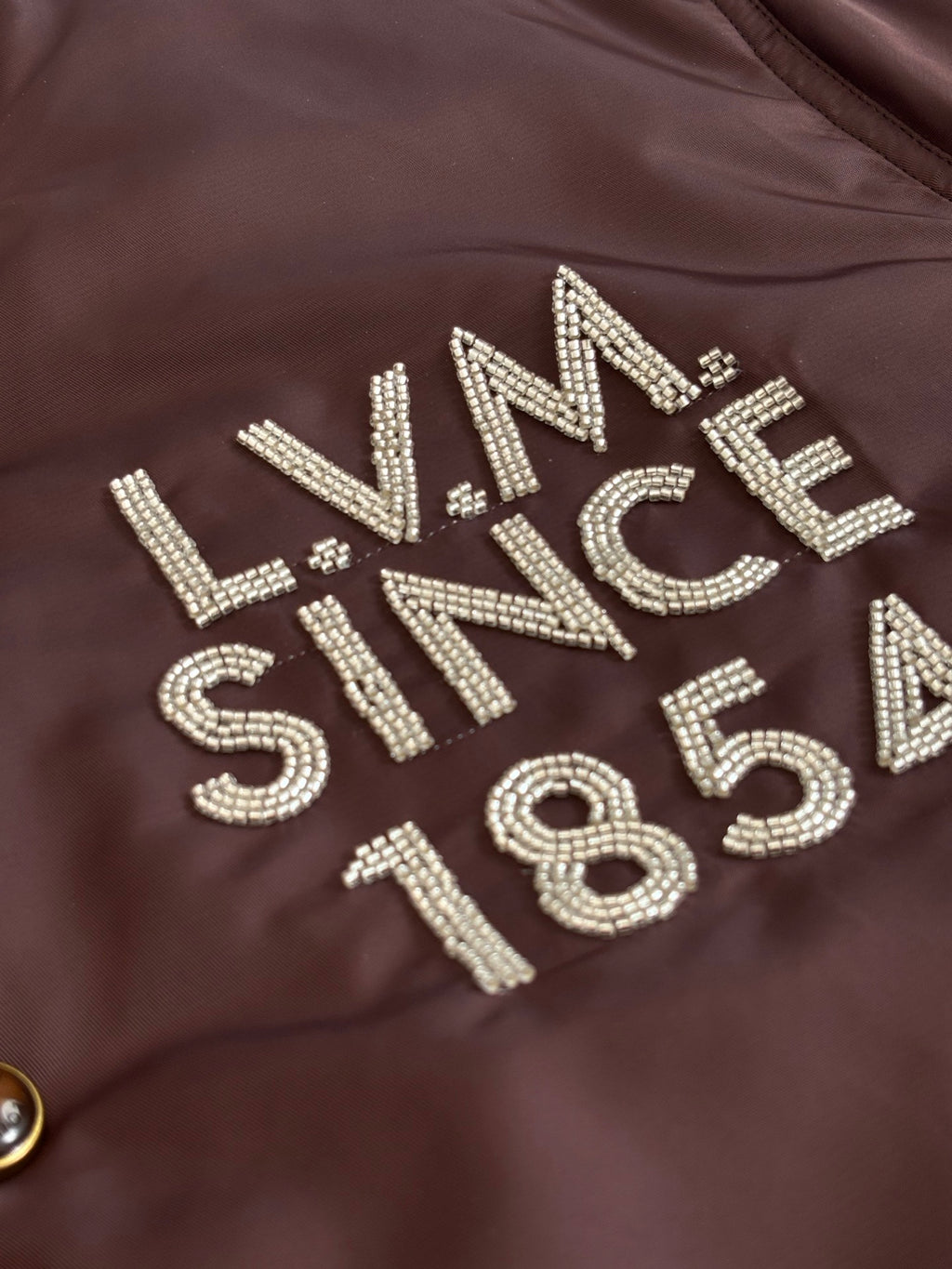 Louis Vuitton long bomber jacket chest rhinestone lettering on dark brown fabric