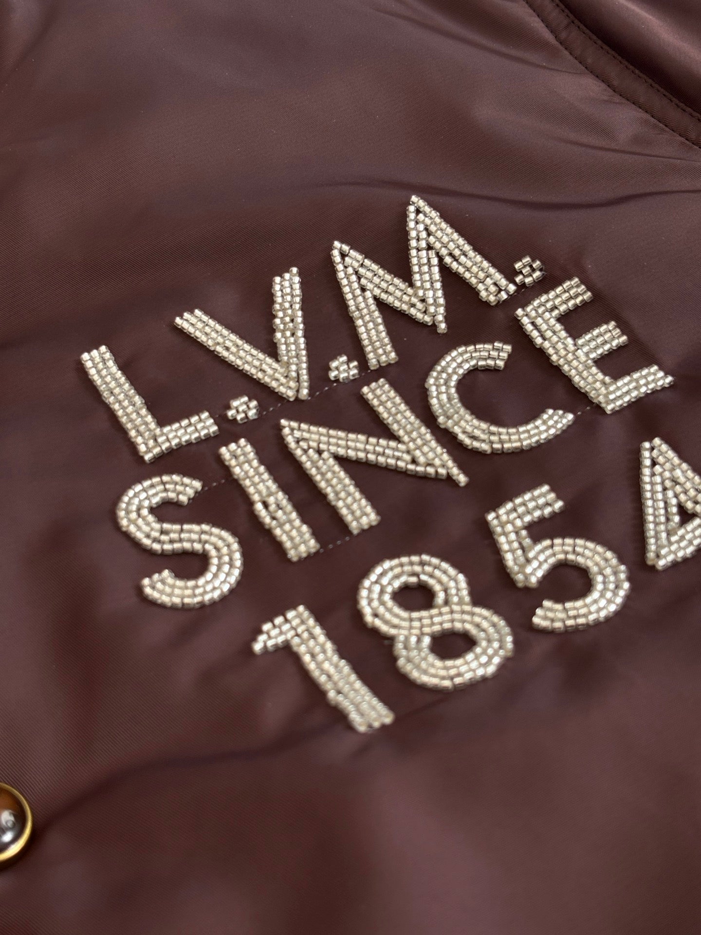 Louis Vuitton long bomber jacket chest rhinestone lettering on dark brown fabric