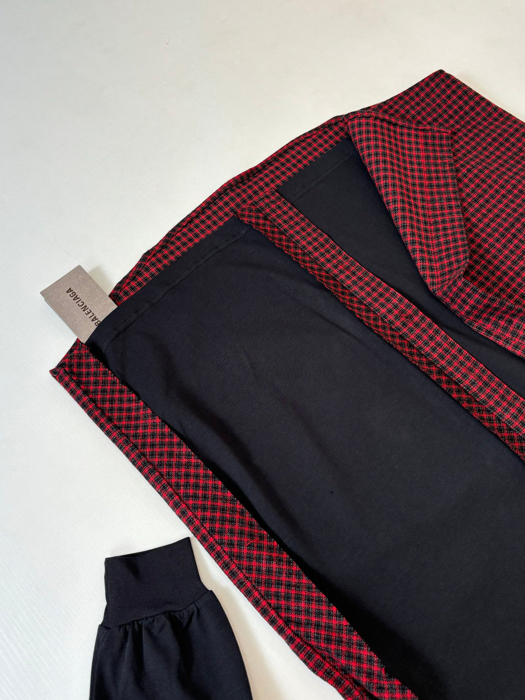 Balenciaga long-sleeve shirt folded flat; red check fabric with black sleeves and cuffs
